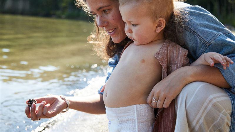 Mother and child shown at the edge of a river.